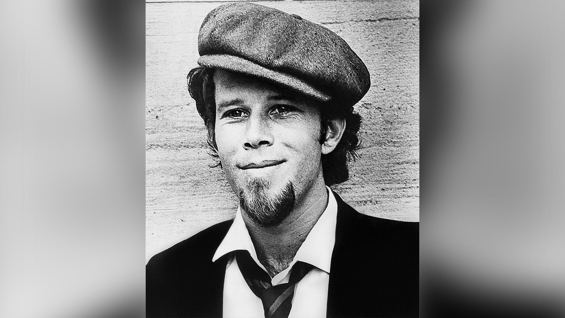 Młody Tom Waits w czapce, uśmiechnięty
