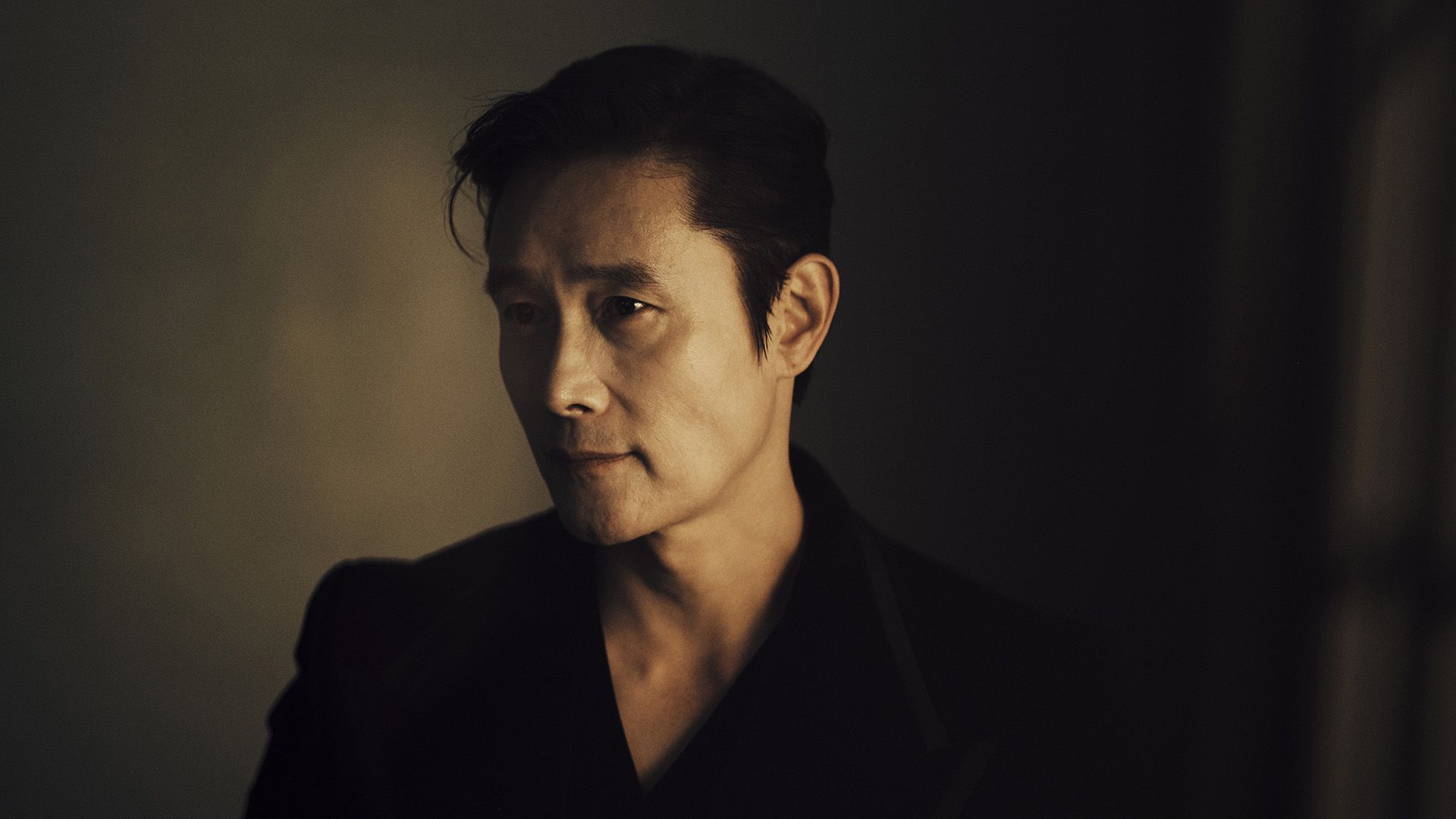 Aktor Lee Byung-hun z profilu w przyćmionym świetle