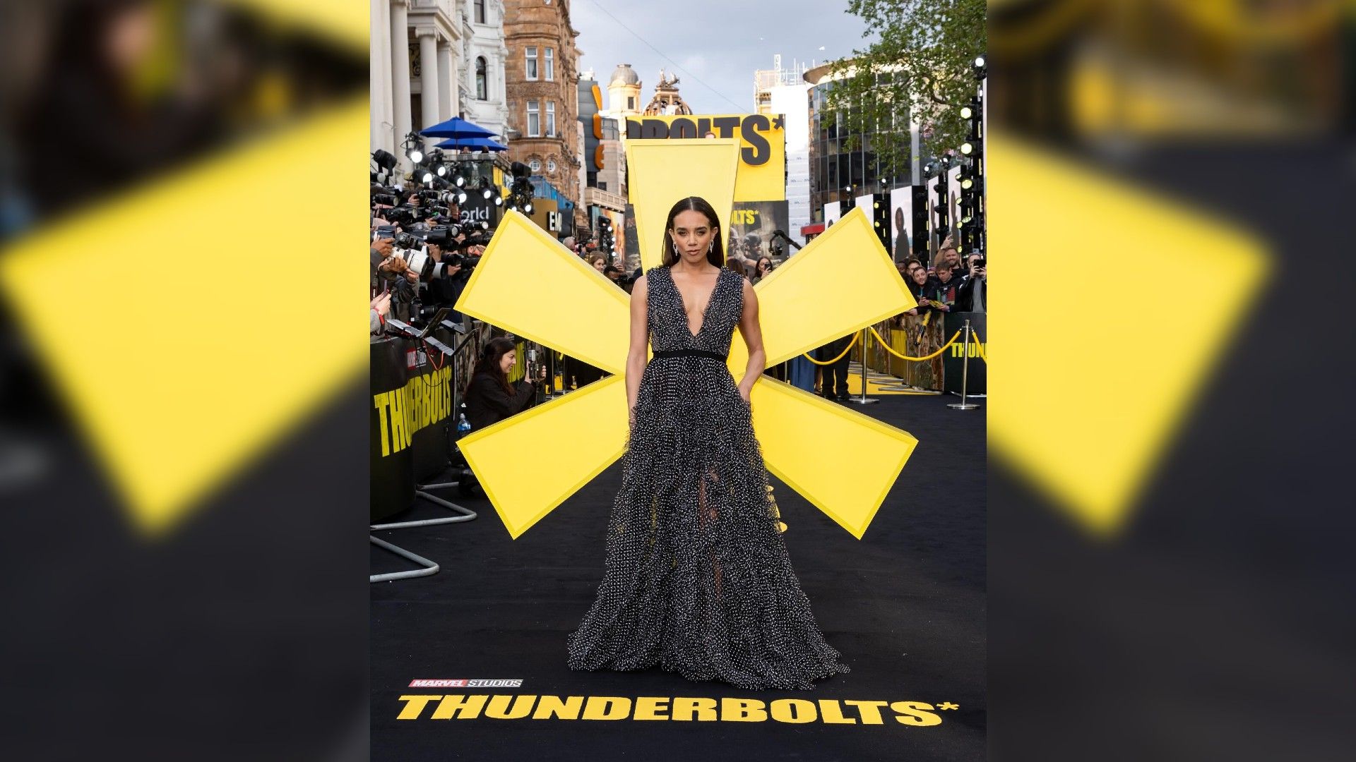 Hannah John-Kamen w długiej sukni na tle ogromnej żółtej gwiazdy