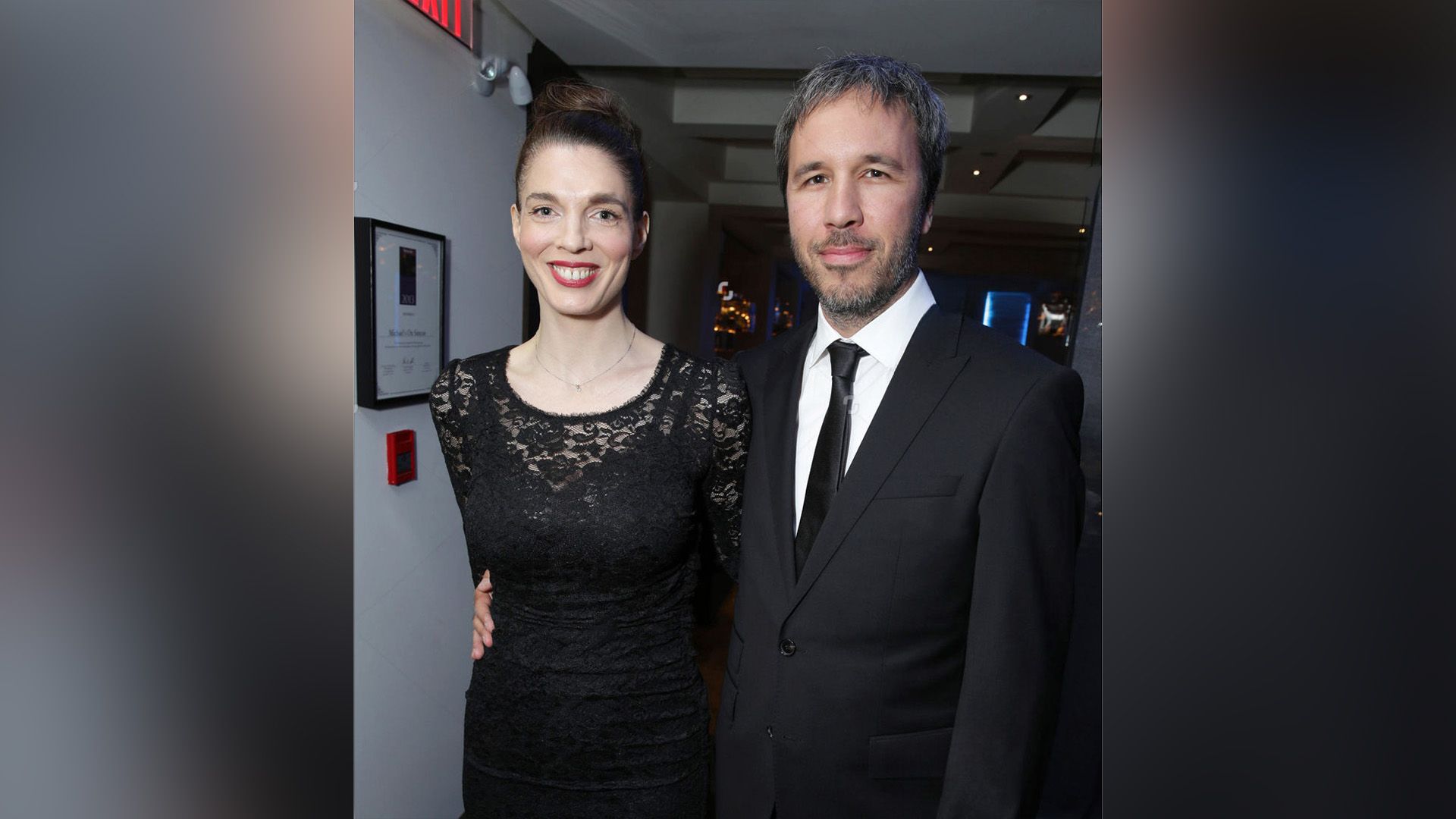 Denis Villeneuve w garniturze obejmuje uśmiechniętą Mashę Grenon w czarnej koronkowej sukience w talii