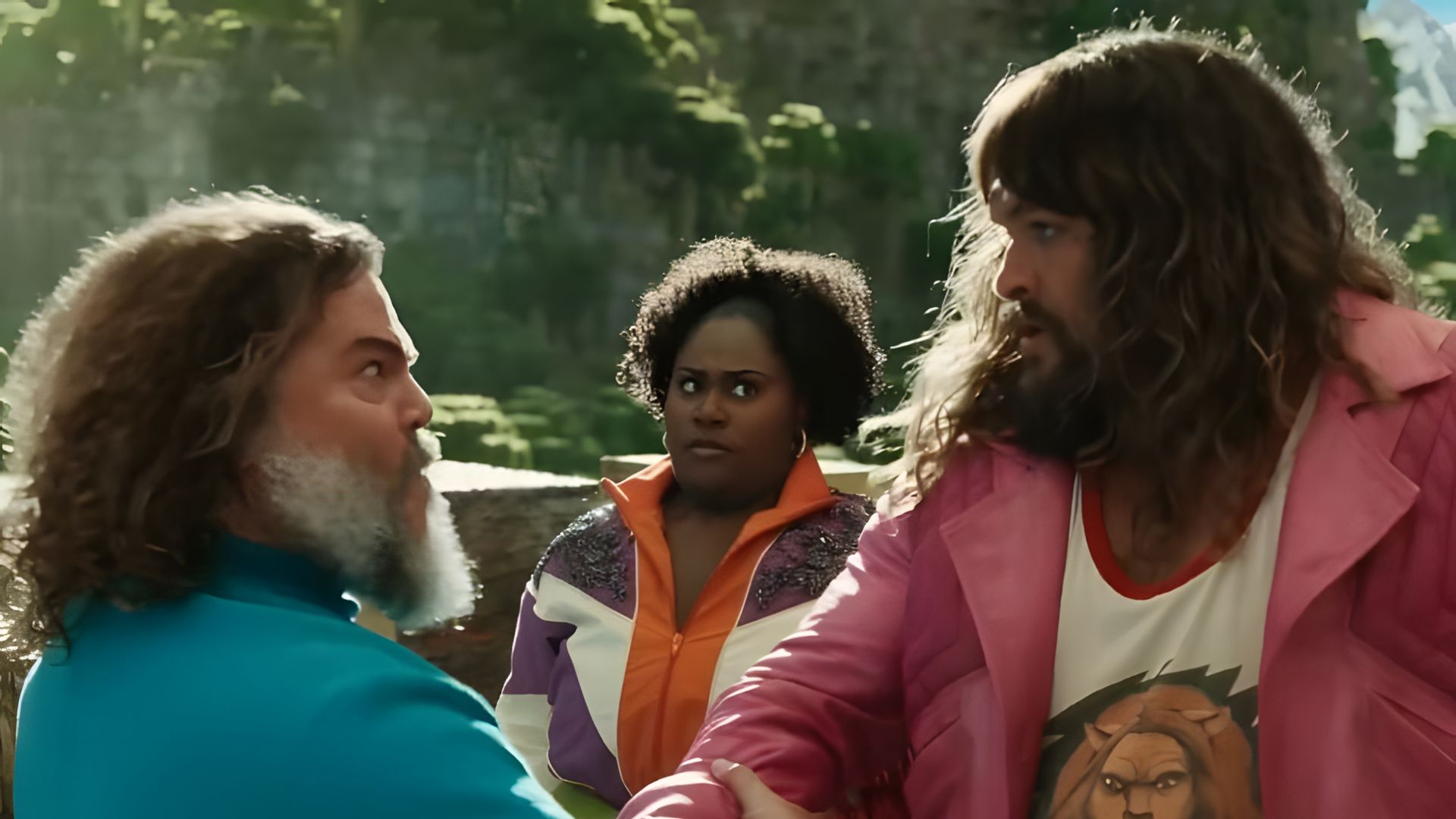 Jack Black w niebieskiej koszulce i Jason Momoa w różowej kurtce energicznie się ściskają za ręce